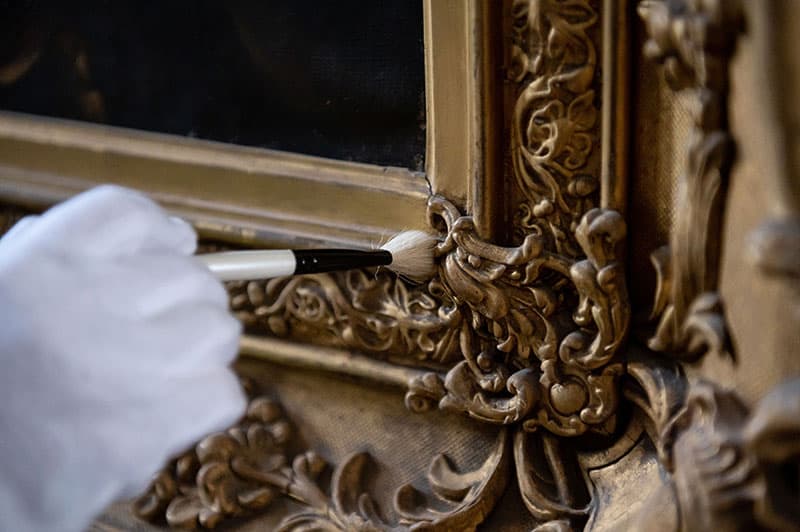 An old picture frame being tended to by a curator.